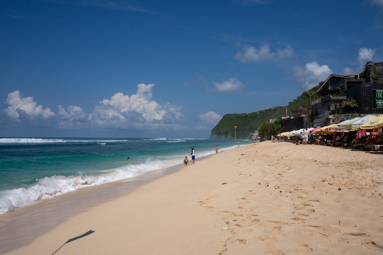 Plage de sable blanc de Bali avec falaises et parasols au soleil